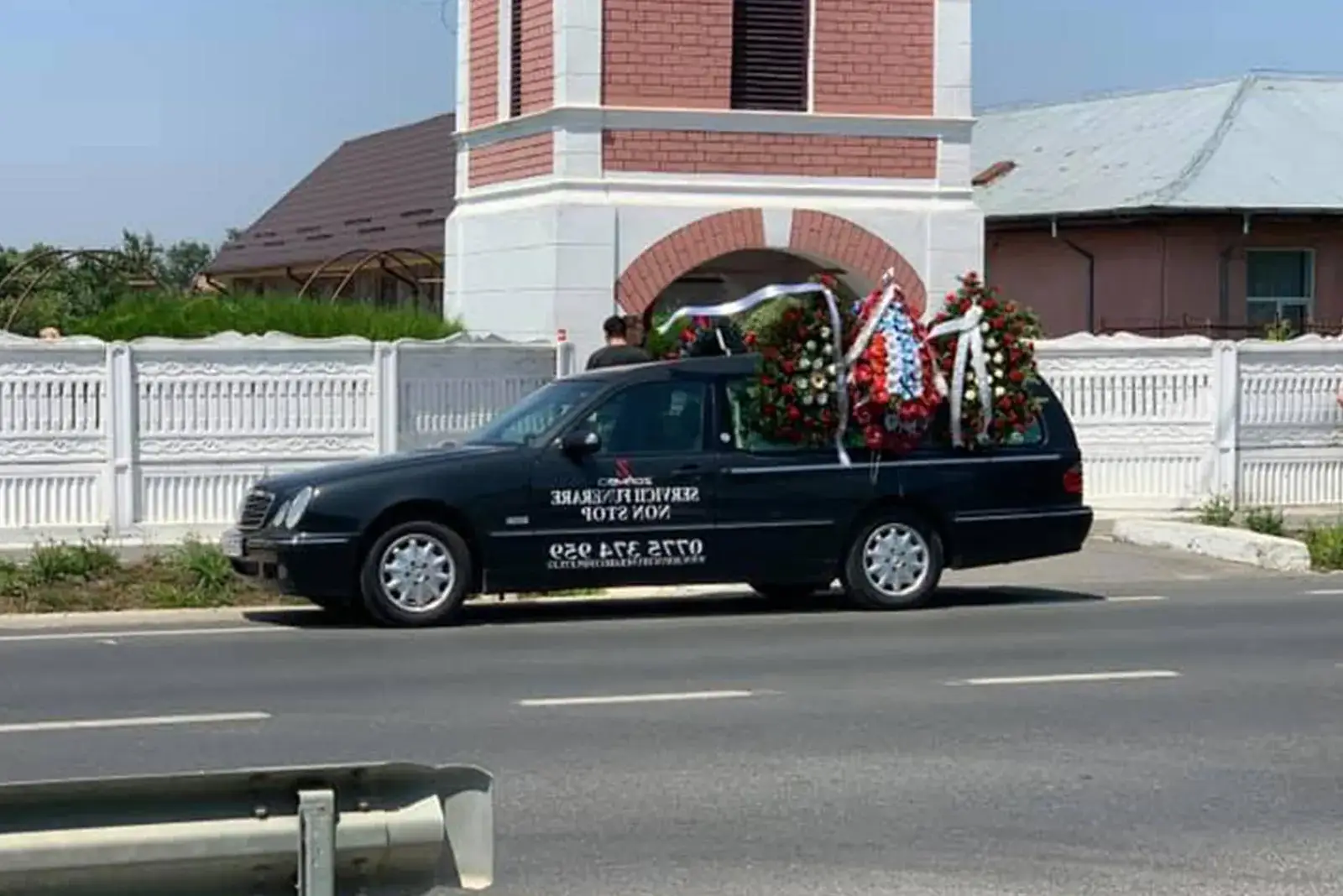 Mașina funerară Zgâmboi cu coroane, în fața unei biserici din Teleorman