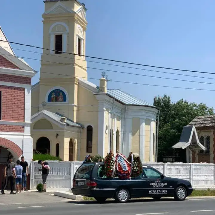 Mașina funerară Zgâmboi în fața unei biserici, în timpul unei înmormântări
