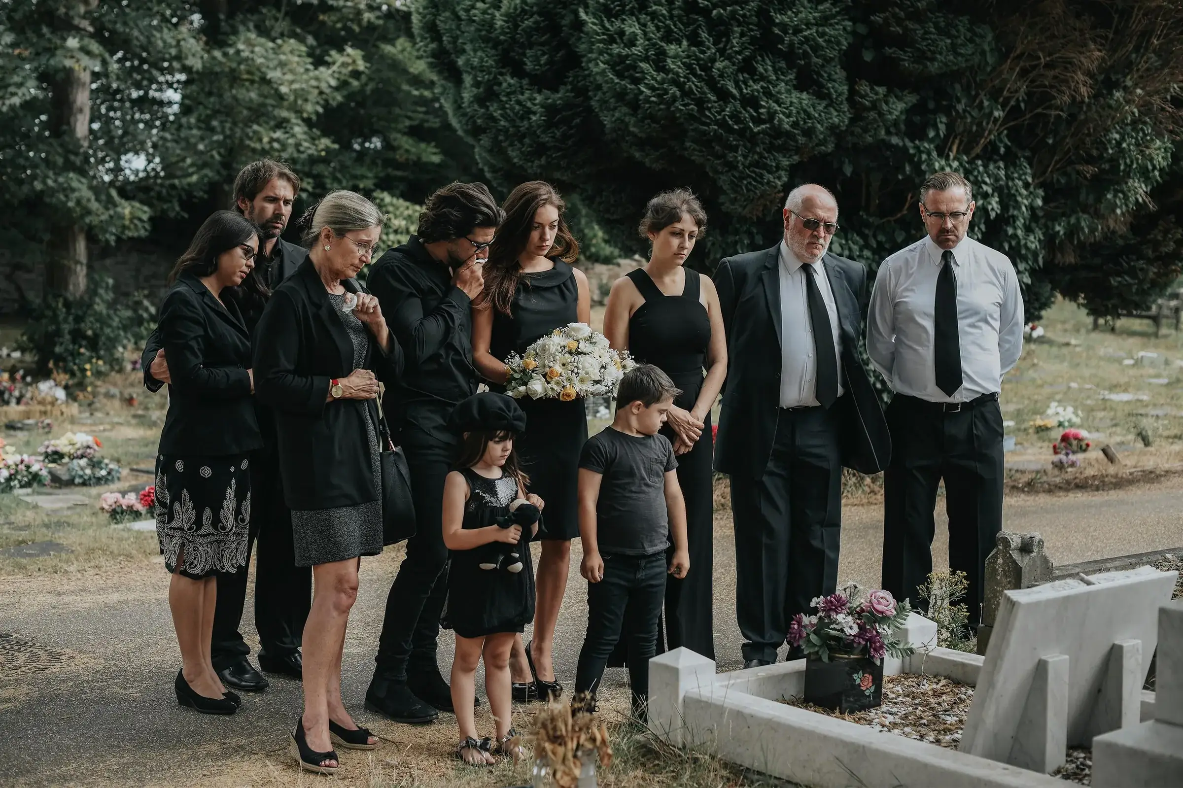 Familie îndoliată, îmbrăcată în negru, la mormânt în ziua înmormântării